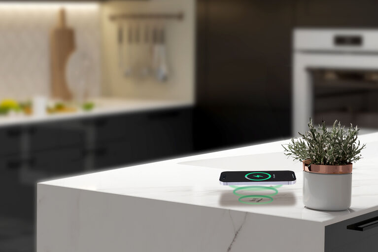 Der Charger Qi kann unsichtbar unter der Arbeitsfläche verschwinden Qi-fähiges Smartphone wird mit Charger Qi geladen